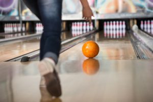 Woman in club for bowling is throwing ball.