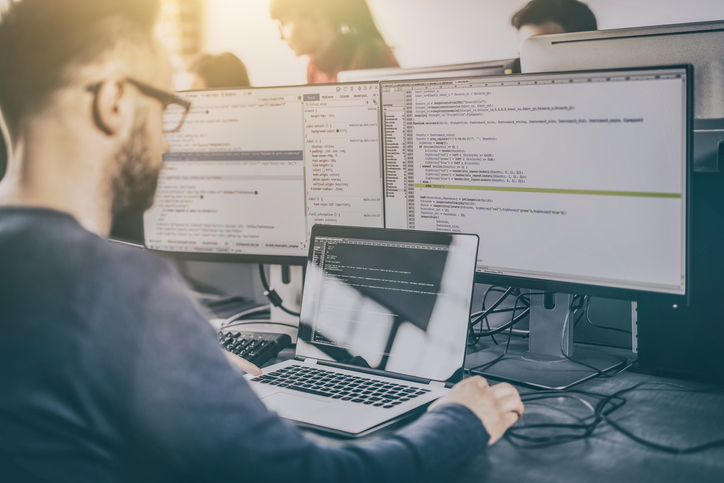 man sitting at computer with code on screen