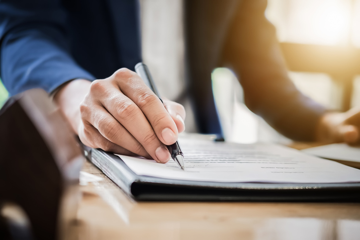 man pointing pen at paper