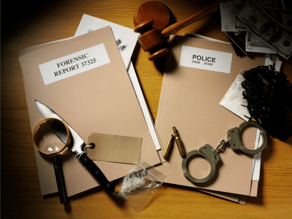 A brown desk is covered in police files, handcuffs, evidence, and a magnifying glass.